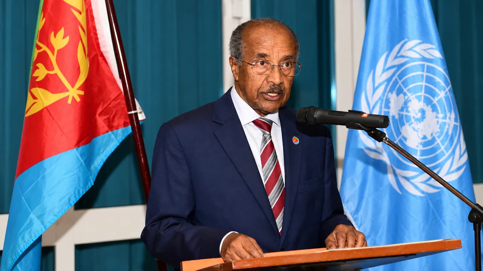 Osman Saleh at a lectern between Eritrean and UN flags.